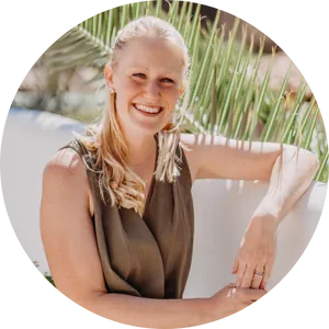 Vicky, a white woman leaning against a white wall outdoors, enjoying a business retreat in Spain