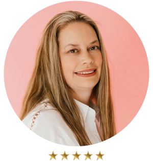 Tracy, a smiling woman with long hair and a white shirt stands confidently against a pink background, embodying the approachable expertise of consulting services for small businesses.