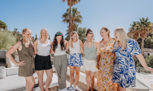 Kate and a group of business women standing together, smiling at the retreat venue outdoors.